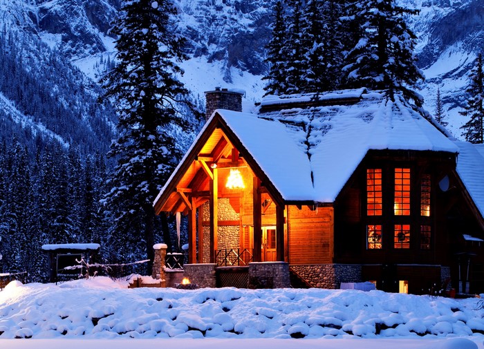 Cozy wooden cabin in a snowy forest at night