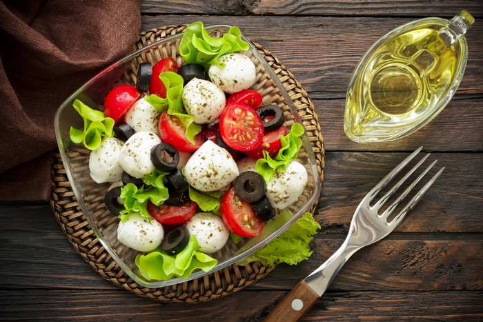 Caprese salad with mozzarella, tomatoes, olives, and lettuce
