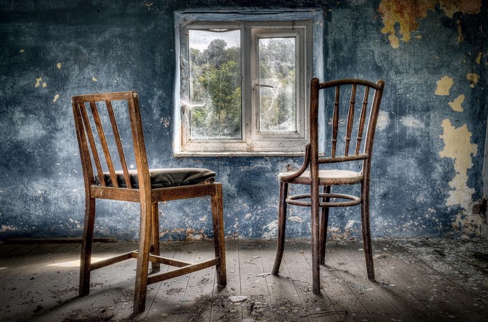 Two chairs in an abandoned room with a window