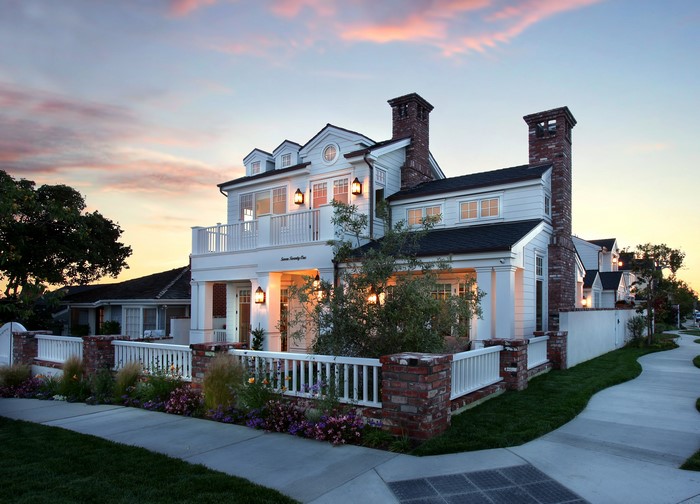 White house with brick chimneys and white fence