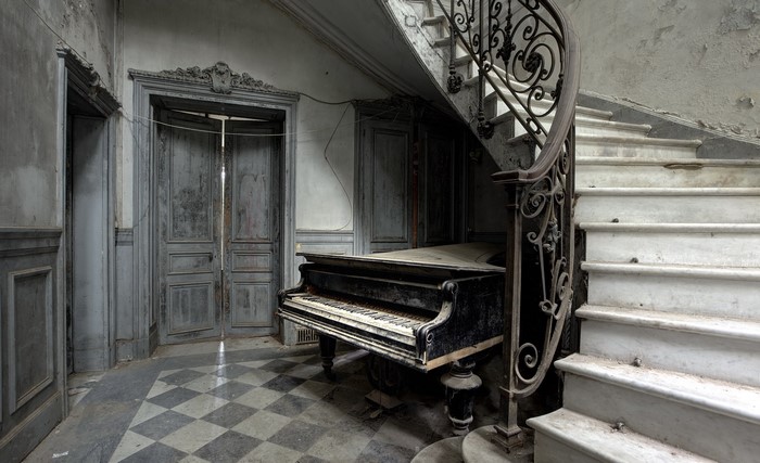 Abandoned grand piano by a marble staircase