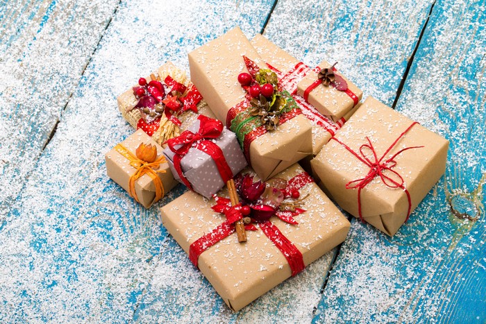 Christmas gifts wrapped in brown paper and tied with red ribbon, dusted with snow