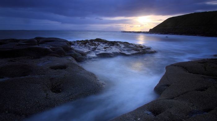 Ocean waves crashing on rocky shore at sunset
