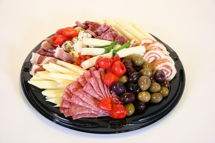 Charcuterie board with meats, cheeses, olives, and tomatoes