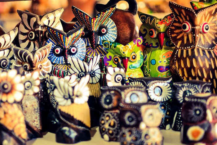 Colorful wooden owl figurines displayed for sale