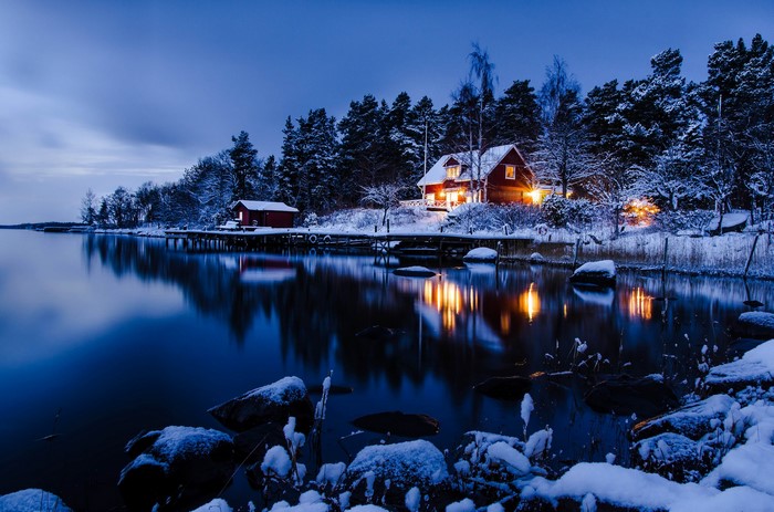 Winter scene with houses by a lake at dusk