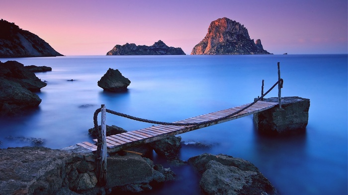 Wooden pier extending into the ocean at sunset