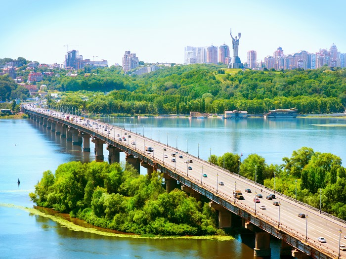 Bridge over river with city and statue in background