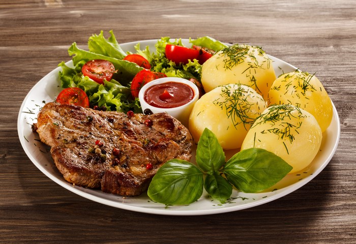 Steak with potatoes, salad, and ketchup
