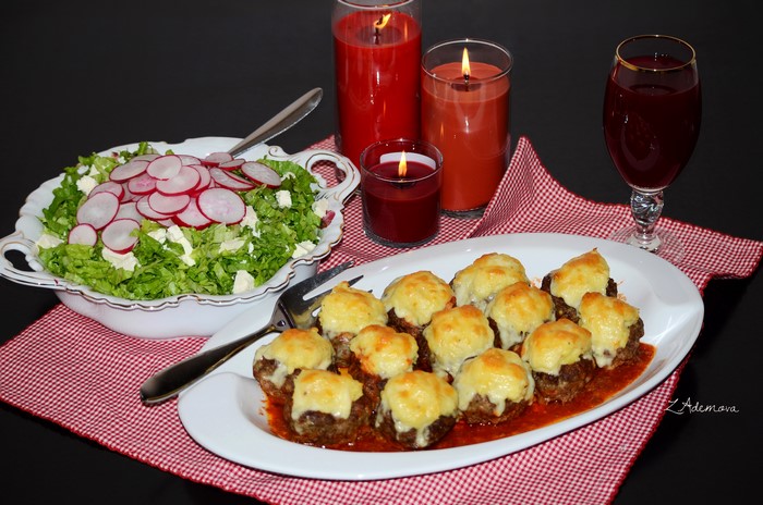 Meatballs with cheese, salad, juice, and candles