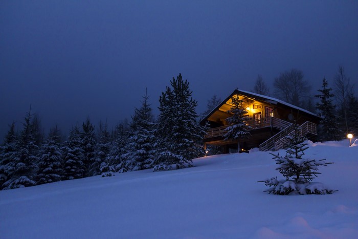 Winter cabin in snowy forest at night