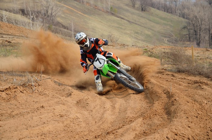 Motocross rider kicking up dust on a dirt track