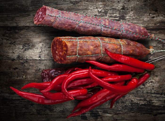 Sausages and red chili peppers on a wooden table