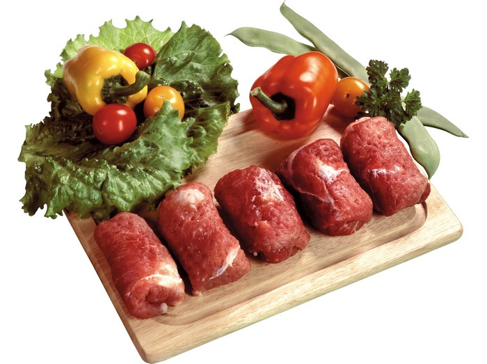 Raw meat rolls with vegetables on a cutting board