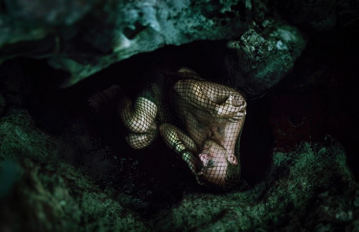 Man trapped in a net in a dark cave