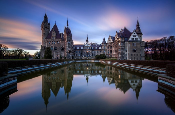 Moszna Castle reflected in pond at sunset, Poland