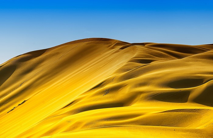 Golden sand dunes under a clear blue sky