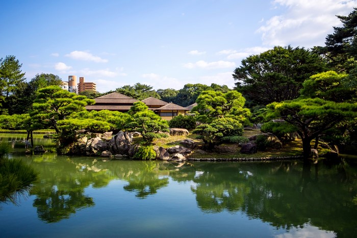Ritsurin Garden pond with traditional Japanese buildings and trees