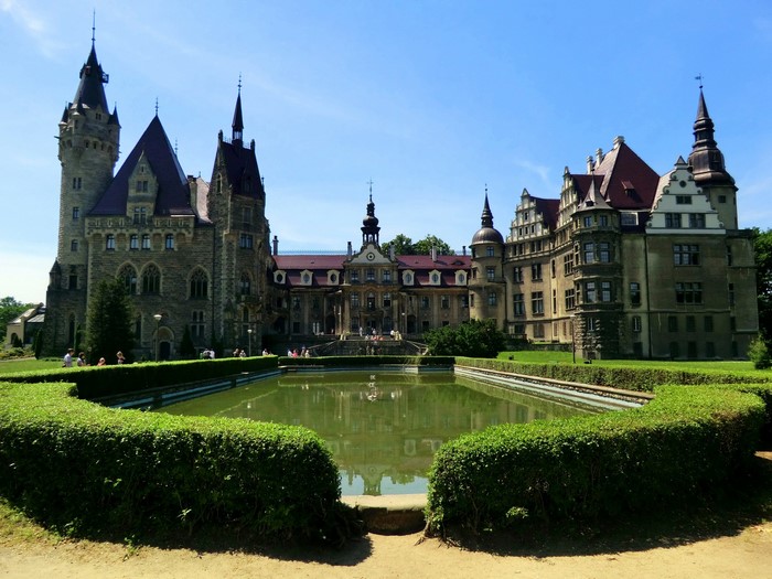 Moszna Castle, Poland with a pond and manicured hedges