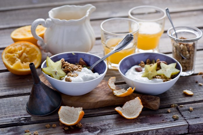 Breakfast with yogurt, granola, oranges, and juice