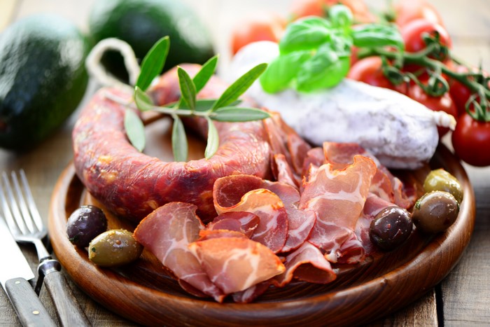 Meat platter with sausage, ham, olives, tomatoes, and avocado