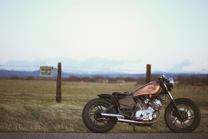 Custom Yamaha motorcycle parked by a fence