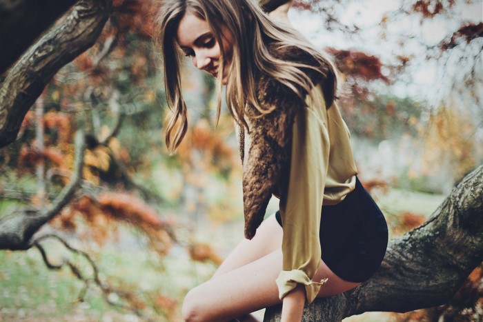Girl sitting on a tree branch in autumn