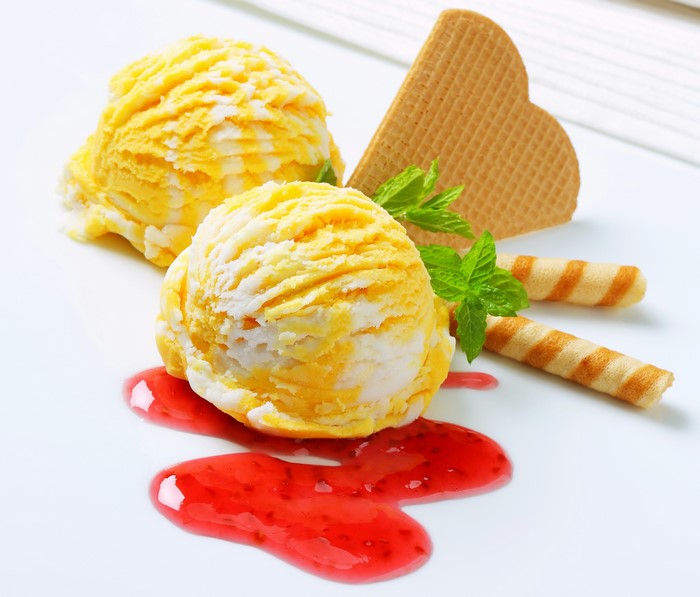 Yellow and white ice cream scoops with jam and cookies