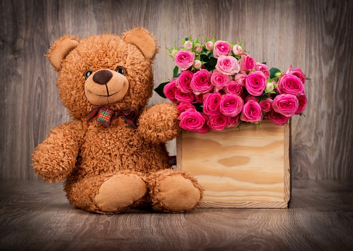 Teddy bear with pink roses in a wooden box