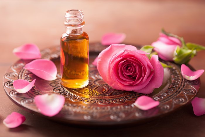 Rose oil in a bottle with pink roses and petals