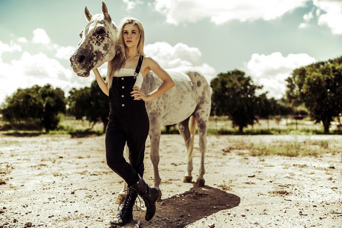 Blonde girl with a horse in a dry field