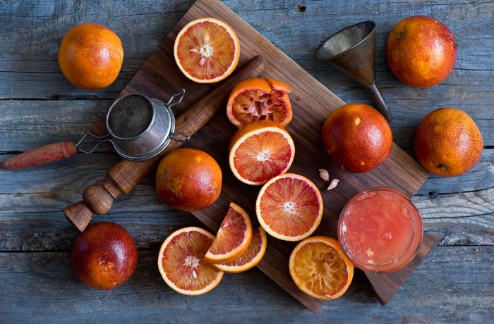 Blood oranges and juicing tools on a wooden table