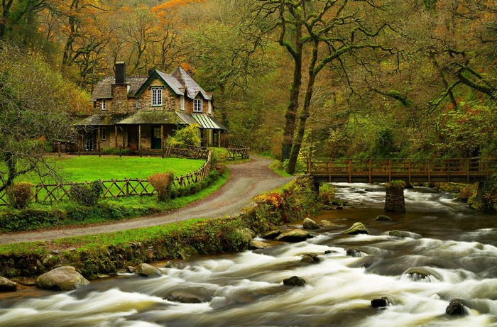 Stone house by a river with a wooden bridge