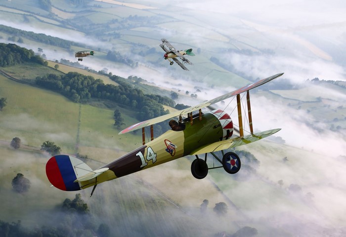 Biplane formation flying over misty countryside