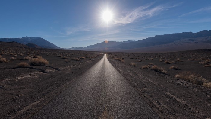 Asphalt road through desert landscape under sun