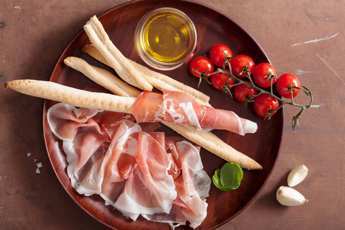 Prosciutto, Breadsticks, Tomatoes, Garlic, and Olive Oil on a Platter