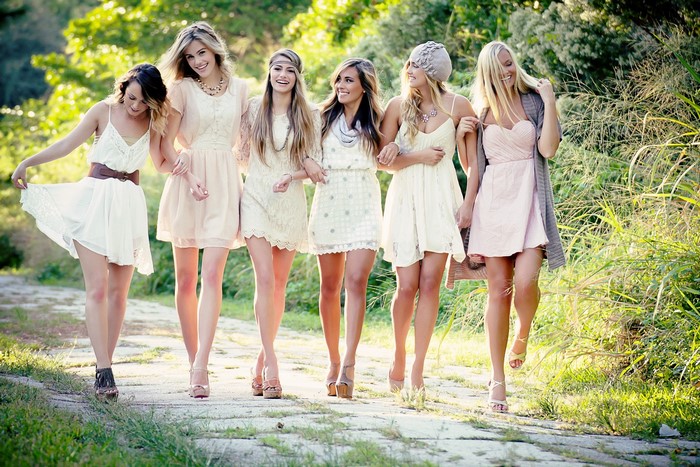 Six young women in dresses walking outdoors