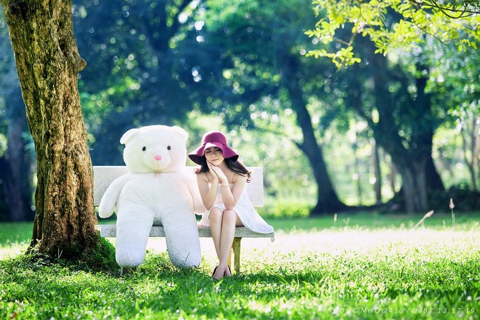 Girl with Teddy Bear on a Bench in a Park