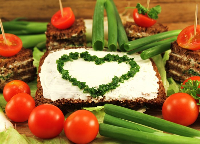 Heart-shaped chives on cream cheese toast with tomatoes and green onions