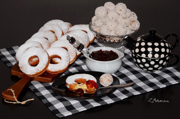 Still-life of powdered donuts with jam and tea set