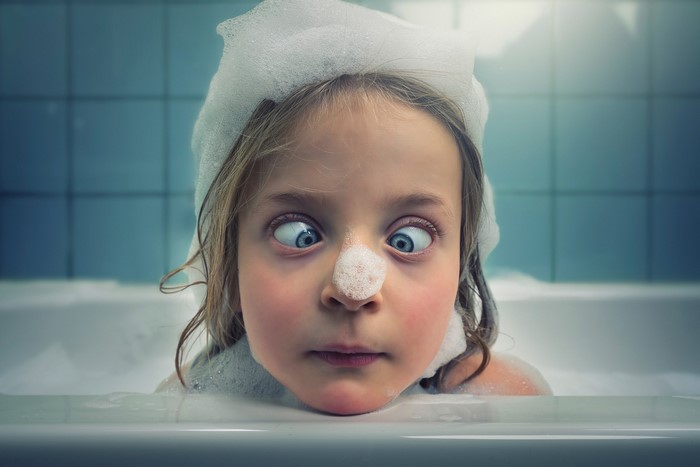Girl with foam on her head in a bathtub