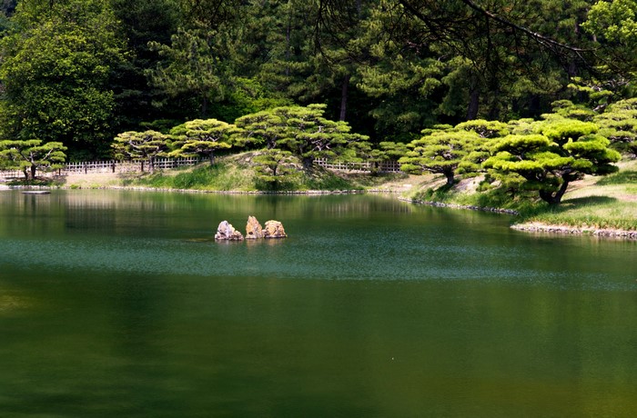 Ritsurin Garden pond with rocks and trees in Japan