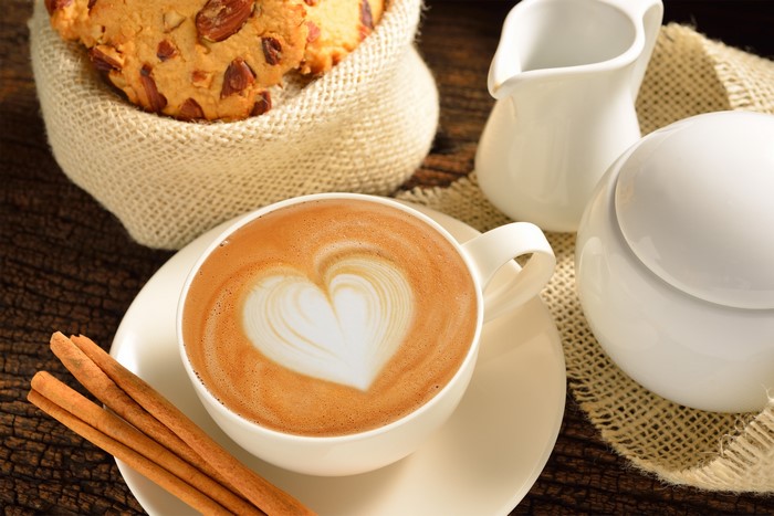Latte art coffee with cookies and cinnamon sticks