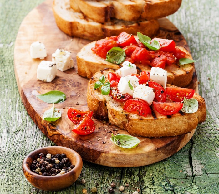 Bruschetta with tomatoes, cheese, and basil on a wooden board