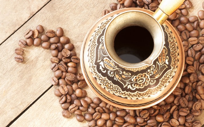 Coffee beans and a cezve on a wooden table
