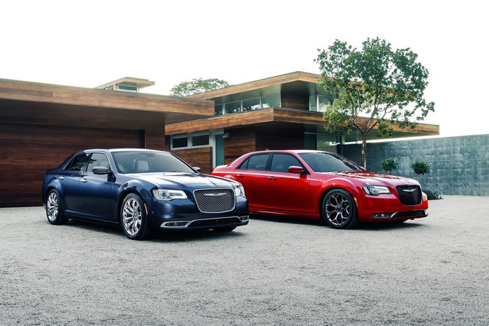 Two Chrysler 300 C sedans parked in front of a modern house