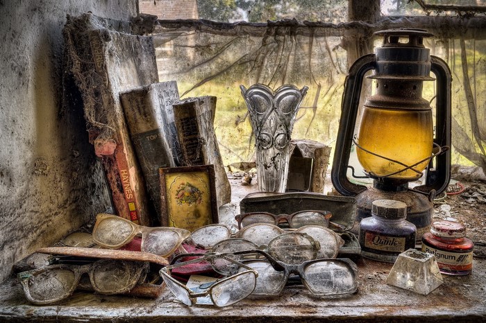 Old books, glasses, and kerosene lamp on a dusty windowsill