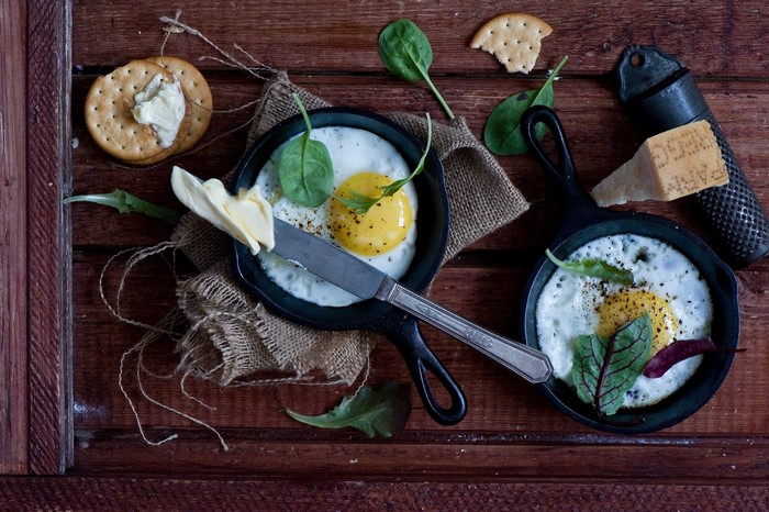 Fried eggs with spinach and crackers on a wooden table