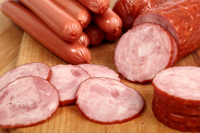 Sausages and sliced meat products on a wooden board