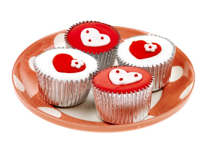 Four Valentine's Day cupcakes with heart decorations on a plate